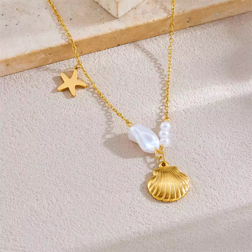 Gold necklace with shell and pearl pendant on a light beige surface