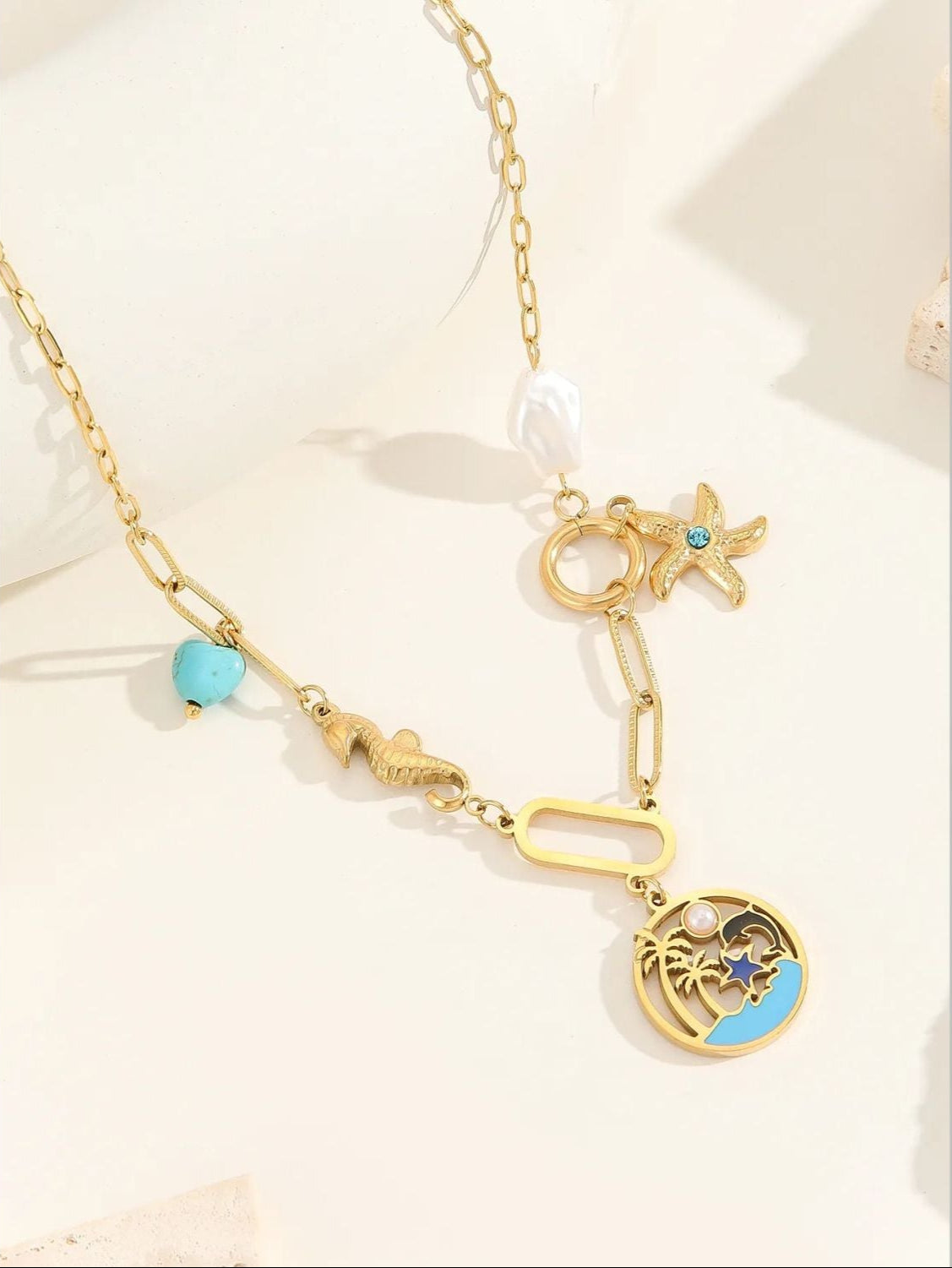 Gold necklace with star and moon charms on a light background